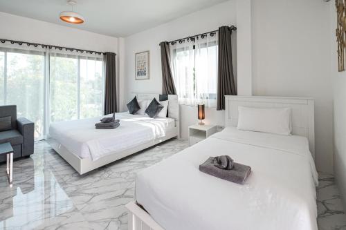 a white bedroom with two beds and a chair at Z-Beach Resort in Ban Nong Ban Kao