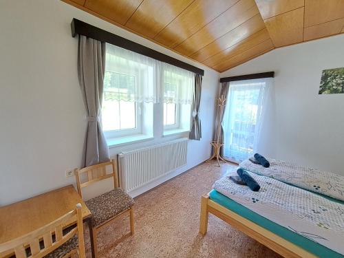 a bedroom with a bed and a chair and windows at Penzion Pochop in Benecko