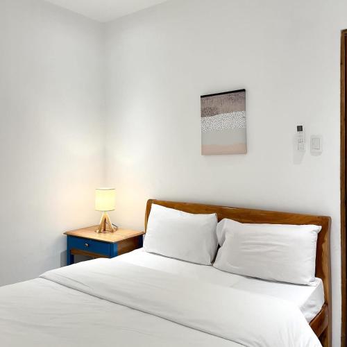 a bed with white sheets and a nightstand with a lamp at Destino Beach Resort and Hotel in Batangas City