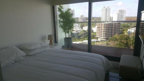 a bedroom with a white bed and a large window at Apartamento Chronos in Punta del Este