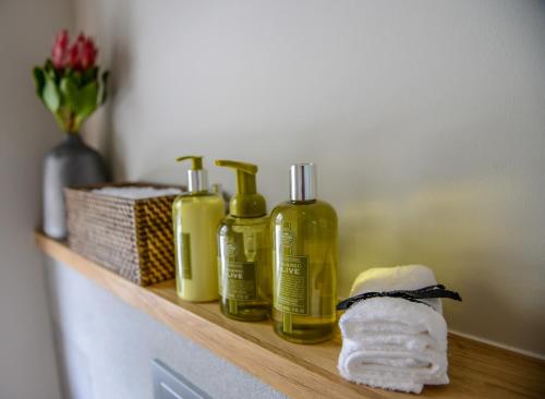 un estante con cuatro botellas de jabón y una toalla en Collection Luxury Apartments 31 Winelands Lodge en Stellenbosch