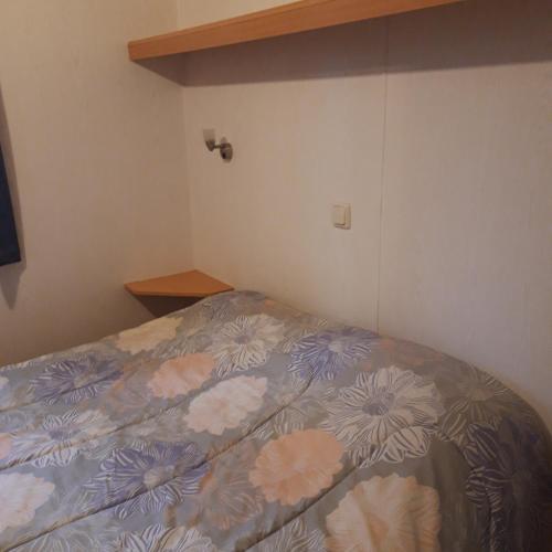 a bedroom with a bed with a floral bedspread at Bungalow a Hyeres prévoir serviettes de toilette et linge de lits in Hyères