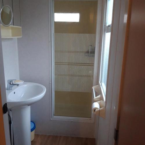 a bathroom with a sink and a glass shower at Bungalow a Hyeres prévoir serviettes de toilette et linge de lits in Hyères