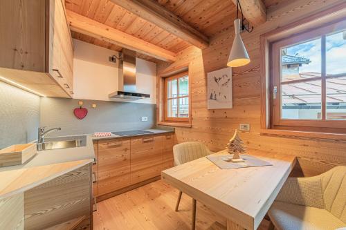 a kitchen with a table and a wooden ceiling at The Love Chalet in Falcade