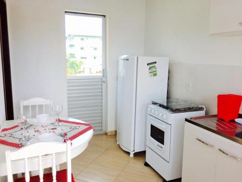 a kitchen with a table and a white refrigerator at Moradas da Bibi in Guarda do Embaú