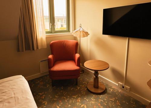 a room with a chair and a table and a television at Havna Hotel & Sjøbad in Tjøme