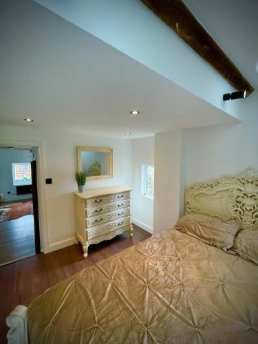 a bedroom with a bed and a dresser with a mirror at Rooftop One-Bedroom Apartment Near East Midlands Airport in Castle Donington