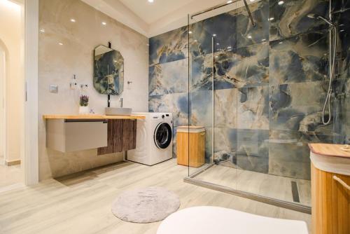 a bathroom with a shower and a washing machine at Luxury Villa Kokos-Private Pool in a Serene Natural Private Estate in Vitalades