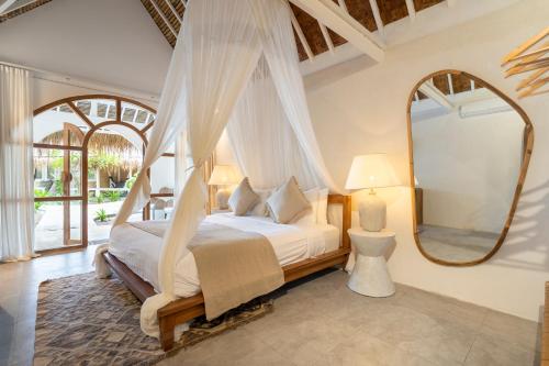a bedroom with a canopy bed and a mirror at Mowies On The Beach in Gili Islands