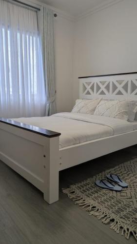a bedroom with a white bed and a window at Oceania Suites 5 Minutes from Jomo Kenyatta international Airport in Nairobi