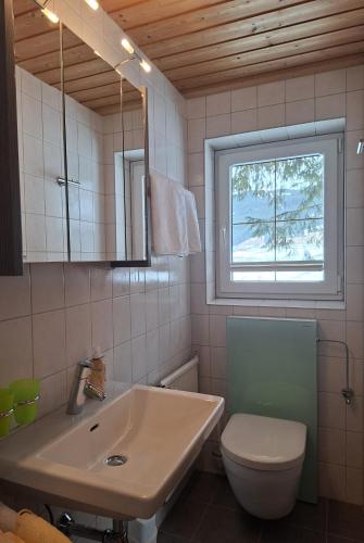 a bathroom with a sink and a toilet and a window at Pension Tannheim in Tannheim