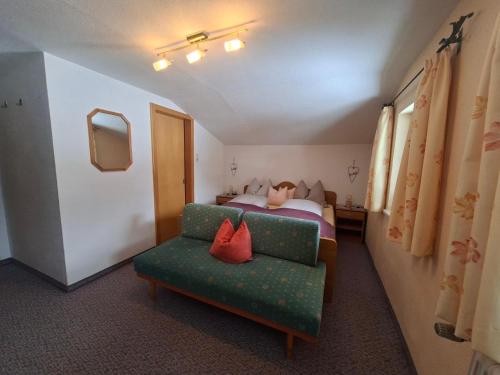 a bedroom with a bed and a couch and a chair at Pension Tannheim in Tannheim