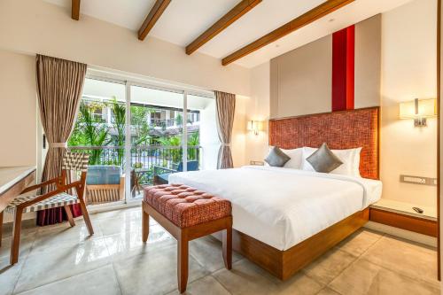 a bedroom with a large bed and a balcony at Mango Hill Hotel Velankanni in Velankanni