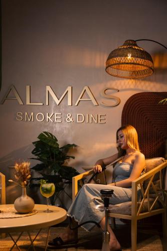 a woman sitting in a chair next to a table at Grand Kingsgate Jaddaf Waterfront Hotel by Millennium in Dubai