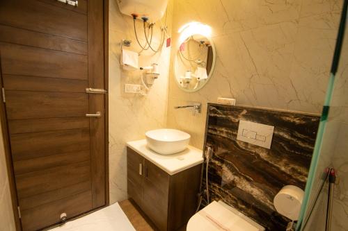 a bathroom with a toilet and a sink and a mirror at Hotel Yog Vashishth in Rishīkesh