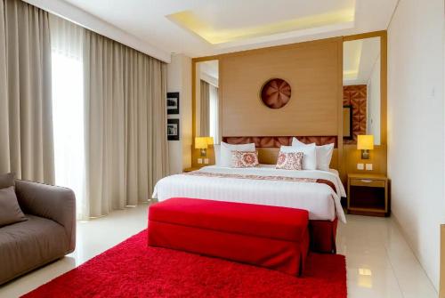 a large bedroom with a large bed and a red ottoman at Ijen Suites Resort & Convention in Malang