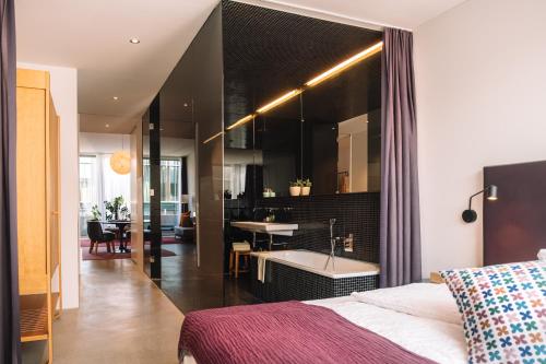 a bedroom with a bed and a bathroom with a tub at Nomad Design & Lifestyle Hotel - Member of Design Hotels in Basel