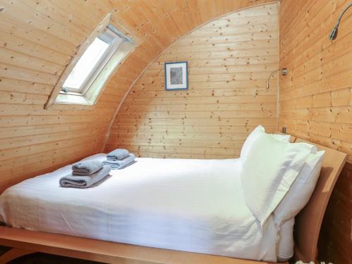 a bed in a wooden room with a window at Grape Escape in Halesworth