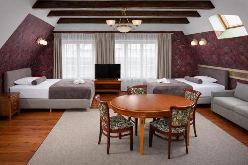 a hotel room with two beds and a table and chairs at Heban Hotel in Toruń
