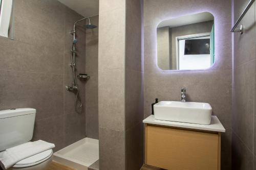 a bathroom with a sink and a toilet and a mirror at Olevia Comfort in Faliraki