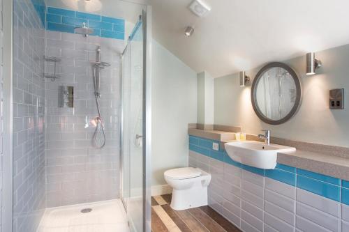 y baño con ducha, aseo y lavamanos. en The Ostrich Inn Colnbrook London Heathrow en Slough