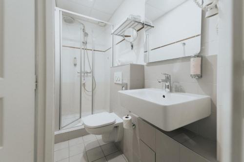 a white bathroom with a sink and a toilet at Hotel Albert 1er in Toulouse