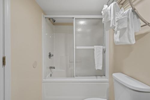 a white bathroom with a shower and a toilet at The Sandbar Hotel, Trademark Collection by Wyndham in Myrtle Beach