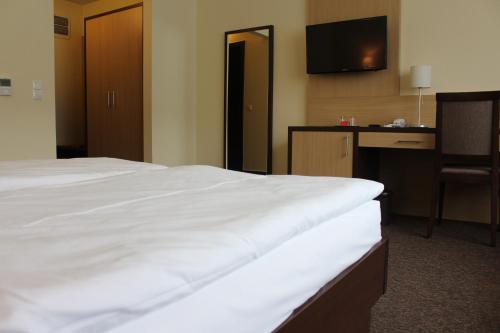 a hotel room with a white bed and a desk at Tokajvár Hotel in Tokaj