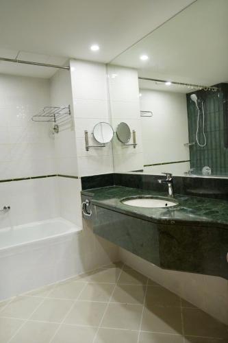 a bathroom with a sink and a tub and a mirror at Al HAYAT PALACE HOTEL in Sharjah
