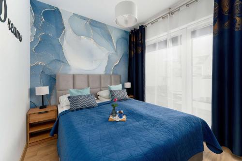 a bedroom with a blue bed with a blue bedspread at Sunset Resort Jasny Apartament z 1 Sypialnią 500 m od Plaży, Balkon & Parking by Noclegi Renters in Grzybowo