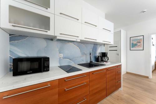 a kitchen with white cabinets and a microwave at Sunset Resort Jasny Apartament z 1 Sypialnią 500 m od Plaży, Balkon & Parking by Noclegi Renters in Grzybowo