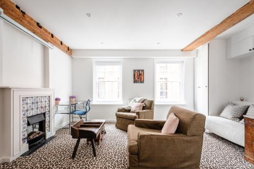 a living room with two chairs and a fireplace at Historic Flat by Liverpool Street in London