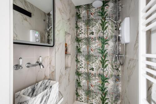 a bathroom with a shower with palm trees on the wall at Historic Flat by Liverpool Street in London