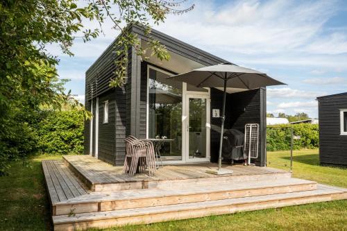 a small house with a deck with an umbrella at DCU-Camping Hesselhus in Silkeborg