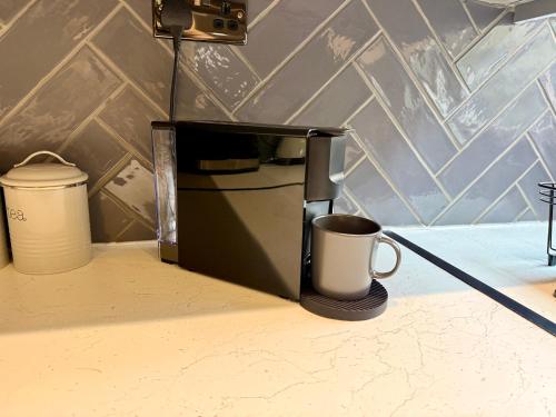 a black coffee maker with a coffee mug in it at Modern City Centre Townhouse sleeps 10 & Parking in Manchester