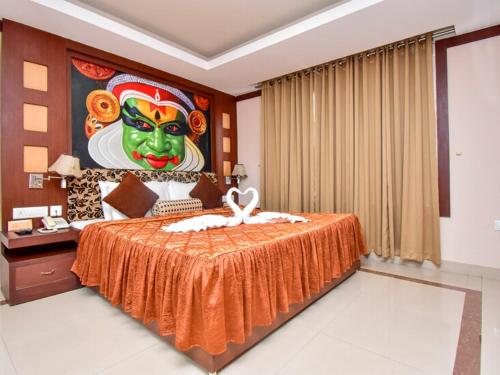 a bedroom with a bed with a painting of a mask at Hotel Sky Pearl in Kannur