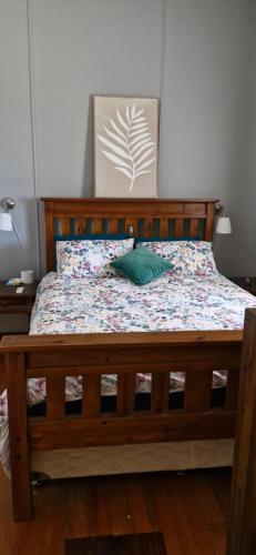 a bed with a wooden frame and a green pillow on it at Himmel Haus in Laguna