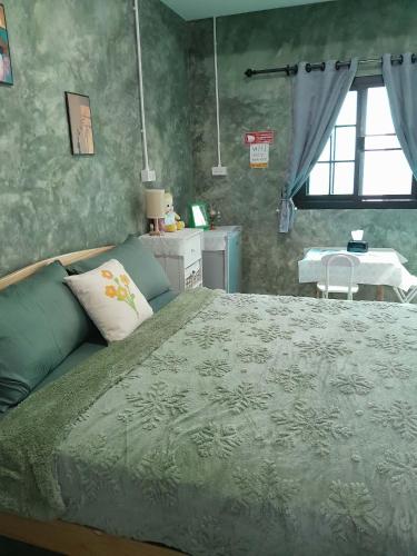 a bedroom with a bed and a table and a window at บ้านอังกาบ Aungkab homestay in Ban Muang Len