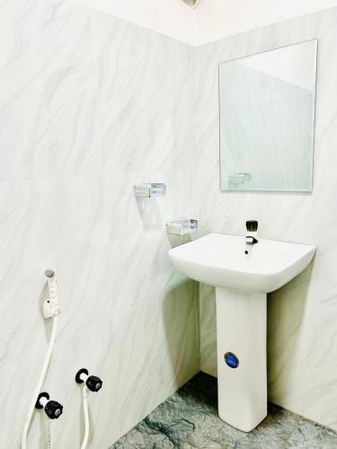 a white bathroom with a sink and a mirror at Thew Guest Wilpattu in Nekattegama