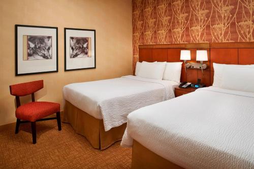 a hotel room with two beds and a red chair at Courtyard Columbus Worthington in Worthington