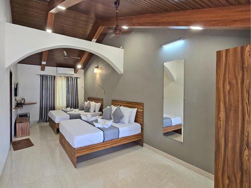 a bedroom with two beds and a mirror at M Beach Resort in Colva