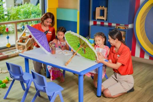 a group of children sitting at a table with umbrellas at Le Meridien Khao Lak Resort & Spa in Khao Lak