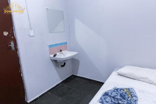 a small bathroom with a sink and a bed at Dom Victor Residence Hotel in Goiânia