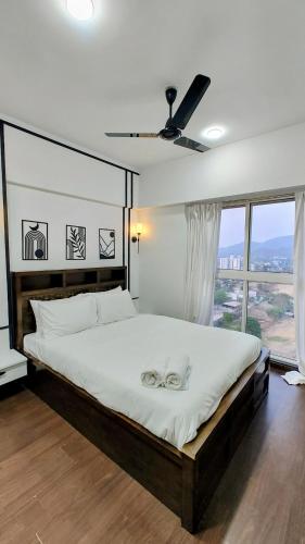 a bedroom with a large bed with a ceiling fan at Monochrome County 16th floor in Dehu Road