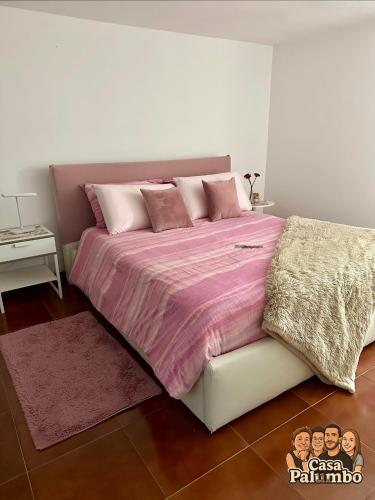 a bedroom with a large bed with a pink comforter at Casa Palumbo in Bacoli