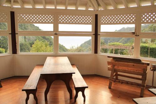 a large room with a wooden table and windows at Aldeia do Sanguinho in Faial da Terra