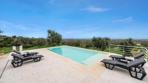 a swimming pool with two lounge chairs and a swimming pool at The Ridge House with Sea View by Rentbeat in Carovigno