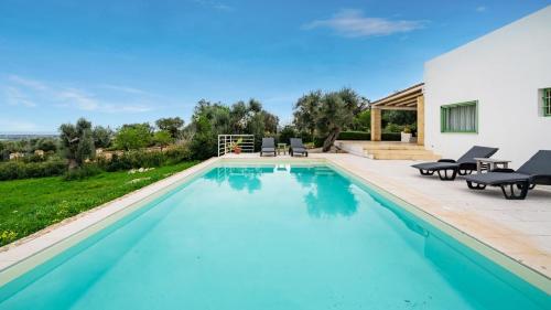 a swimming pool with blue water in a backyard at The Ridge House with Sea View by Rentbeat in Carovigno