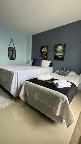 two beds in a bedroom with blue walls at Flat JK 101 in Juazeiro do Norte