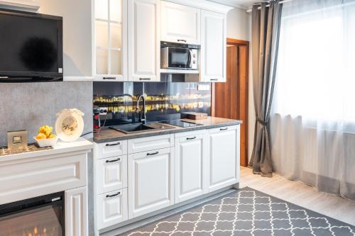 a kitchen with white cabinets and a sink at Apartamenty Blisko Centrum in Toruń